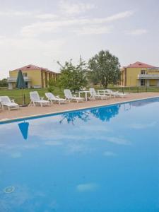 einen Pool mit weißen Stühlen und blauem Wasser in der Unterkunft Eurhotel in Fontevivo