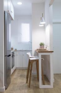 a white kitchen with a wooden table and a counter at El Rincón Encantado in Cuenca