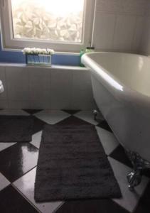a bathroom with a white tub and a black and white floor at 4 Bedroom House For Corporate Stays in Kettering in Isham