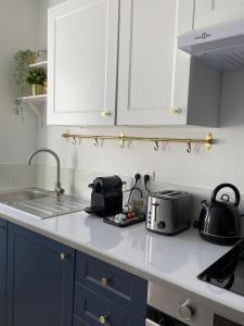 eine Küche mit weißen Schränken und einer Arbeitsplatte mit Töpfen und Pfannen in der Unterkunft L'Appartement Bleu - Logement cosy - Cœur de ville in Douai + 3 Fotos