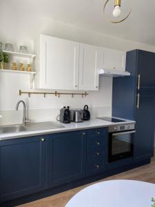 eine blaue Küche mit weißen Schränken und einem Waschbecken in der Unterkunft L'Appartement Bleu - Logement cosy - Cœur de ville in Douai