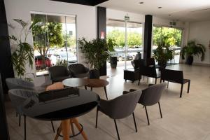 uma sala de espera com mesas, cadeiras e janelas em Hotel Araguaia em Palmas