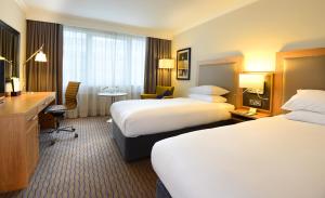 a hotel room with two beds and a desk at Clayton Hotel Burlington Road in Dublin