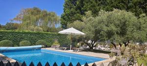 a swimming pool with an umbrella next to a garden at VILLA LE CLOS DES OLIVIERS, piscine chauffée, 5 chambres, jardin de 2500m2, proche plage in Léon