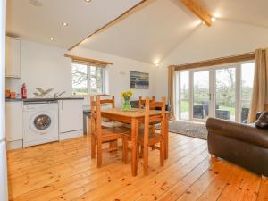 a kitchen and living room with a wooden table and chairs at Vine Cottage in Saint Ewe