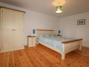 a bedroom with a bed and a dresser in it at Vine Cottage in Saint Ewe