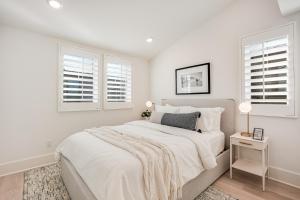 a white bedroom with a bed and two windows at Bayside Cove Estate in San Diego