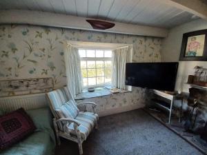 GolantにあるTruly Paradise Cottageのリビングルーム(テレビ、ソファ、窓付)