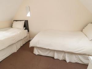 two beds in a room with white sheets at No 1 Low Hall Cottages in Scalby