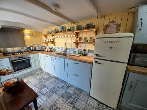 a kitchen with a white refrigerator and a table at Truly Paradise Cottage in Golant