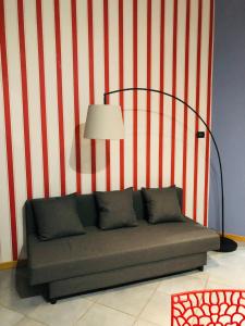 un sofá contra una pared de rayas rojas y blancas con una lámpara en Residenza Avogadro, en Turín
