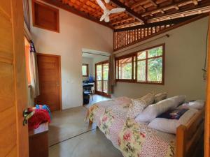 a bedroom with a bed in a room with windows at Chalés Cumuruxatiba in Cumuruxatiba