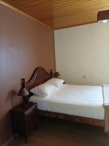 Schlafzimmer mit einem Bett mit weißer Bettwäsche und einer Holzdecke in der Unterkunft Casa de Penim in Paredes de Coura