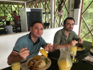 萊蒂西亞的住宿－AMAZONAS RESERVA Yavary Tucano，两个人坐在桌子上,拿着一盘食物