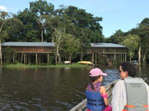 two children in a boat on the water with a building at Reserva Yavary Tucano in Leticia