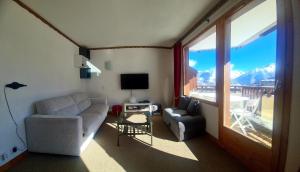 a living room with a couch and a chair and a window at Résidence Saboia Courchevel La Tania - Belle Vue in Courchevel