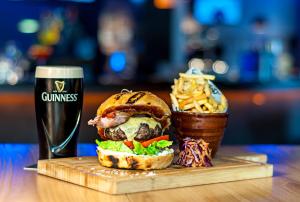 a sandwich and a glass of beer and a basket of fries at Clayton Hotel Burlington Road in Dublin