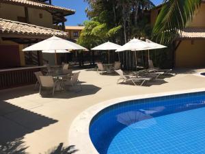 - une piscine avec des chaises et des parasols à côté d'un bâtiment dans l'établissement O paraíso na terra tem nome: Praia do Forte, à Praia do Forte