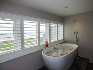 a white bath tub in a bathroom with windows at Sea View Apartment in Llanfairfechan +15 photos