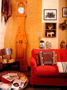 a living room with a grandfather clock and a red couch at Hotel Vallée De Cogne in Cogne