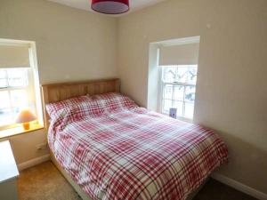 ein Schlafzimmer mit einem Bett mit einer karierten Decke in der Unterkunft 1A Market Square in Tideswell