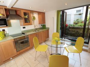 a kitchen with a glass table and yellow chairs at Mill Bridge Cottage in Castleton