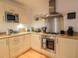 a kitchen with white cabinets and a stove top oven at Fistral Outlook in Crantock