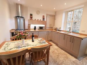 a kitchen with a wooden table with chairs and a sink at Netherlea Cottage in Highpeak Junction