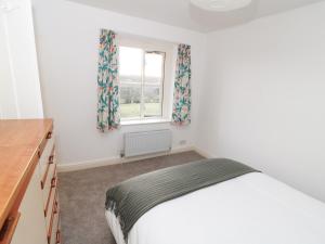 a bedroom with a bed and a window at Netherlea Cottage in Highpeak Junction