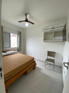 Schlafzimmer mit einem Bett, einem Deckenventilator und einem Stuhl in der Unterkunft Apartamento com excelente localização e conforto! in Ubatuba