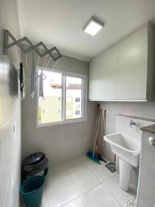 baño con lavabo y aseo y ventana en Apartamento com excelente localização e conforto!, en Ubatuba
