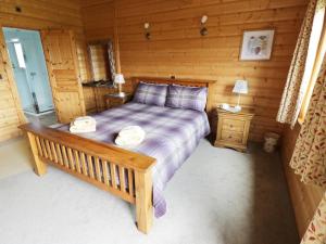 a bedroom with a bed in a log cabin at Look Out Lodge in Little Witley