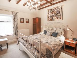 a bedroom with a large bed and a chandelier at Hawthorn Cottage in Eyam