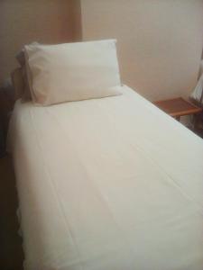 a white bed with a pillow on top of it at The Principality 2 Singles Bedroom in Cardiff