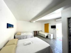 a hotel room with two beds and a tv at Pousada Kawaii in Arraial d'Ajuda