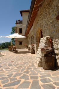 a stone patio with an umbrella next to a building at Le Clos de Lumière in La Roche-des-Arnauds