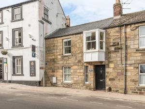 an old stone building on the side of a street at Jackson Cottage in Alnwick