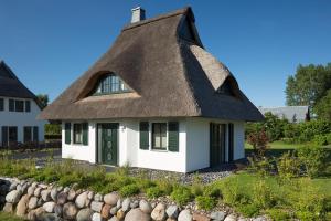 a thatch roofed house with a yard at Ferienhaus Seeadler 7 in Fuhlendorf