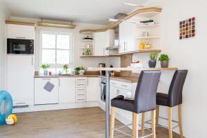 a kitchen with white cabinets and black bar stools at Ferienhaus Schilfrohrsaenger 43 in Fuhlendorf