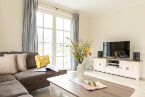 a living room with a couch and a tv at Ferienhaus Seeschwalbe 10 in Fuhlendorf