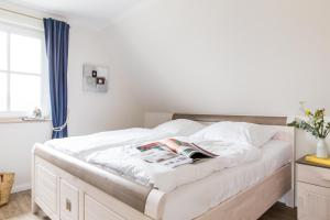 a bedroom with a bed with a book on it at Ferienhaus Seeschwalbe 10 in Fuhlendorf