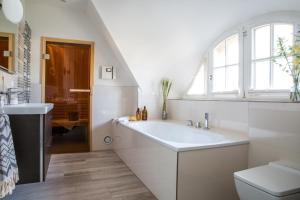 a white bathroom with a sink and a toilet at Ferienhaus Seeadler 3 in Fuhlendorf +25 photos