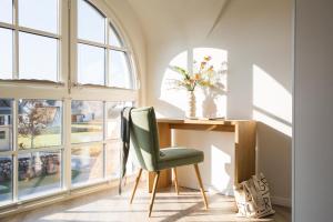 Cette chambre dispose de fenêtres et d'un bureau avec une chaise verte. dans l'établissement Ferienhaus Schilfrohrsaenger 6, à Fuhlendorf