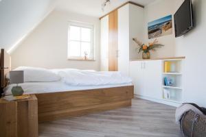 a bedroom with a bed with a tv on the wall at Ferienhaus Schilfrohrsaenger 6 in Fuhlendorf