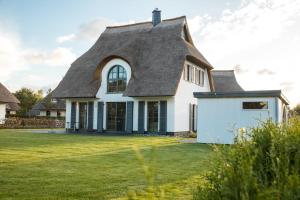 a large white house with a gambrel roof at Ferienhaus Schilfrohrsaenger 6 in Fuhlendorf