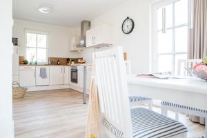 a kitchen with white cabinets and a white counter top at Ferienhaus Schilfrohrsaenger 51 in Fuhlendorf +23 photos