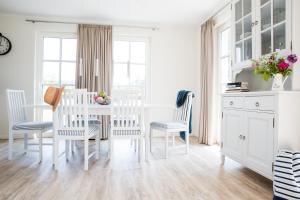 a white dining room with a table and chairs at Ferienhaus Schilfrohrsaenger 51 in Fuhlendorf