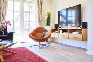 a living room with a chair and a television at Ferienhaus Seeadler 34 in Fuhlendorf