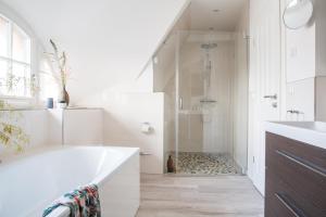 a white bathroom with a tub and a shower at Ferienhaus Seeadler 9 in Fuhlendorf +24 photos