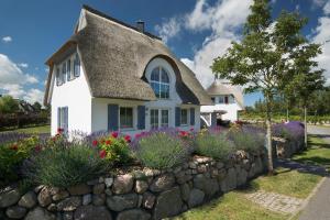 a cottage with a thatched roof and a stone wall at Ferienhaus Schilfrohrsaenger 28 in Fuhlendorf